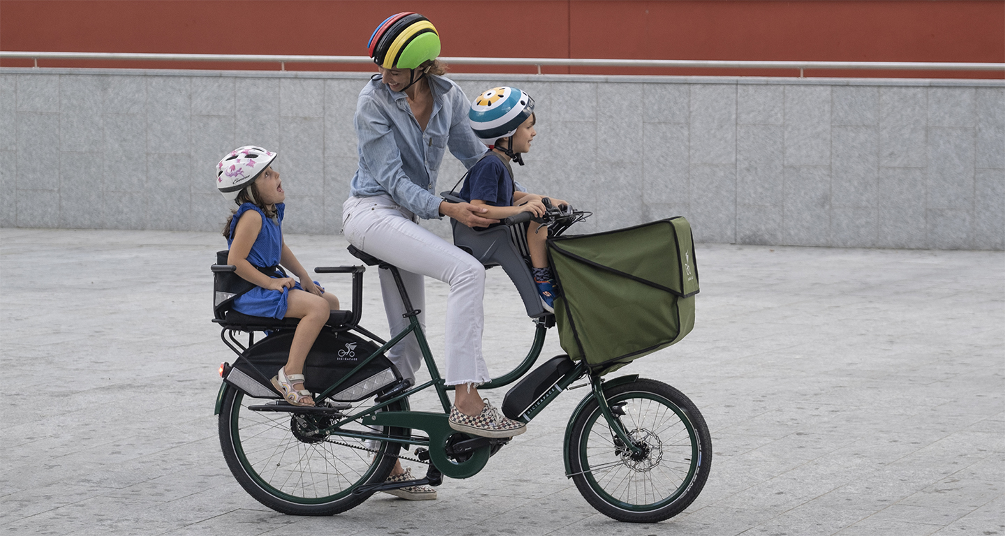 A woman with 2 children on a Bicicapace Classicona cargo bike
