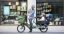 A man sitting on a green Bicicapace Justlong cargo bike with 2 children on the tail
