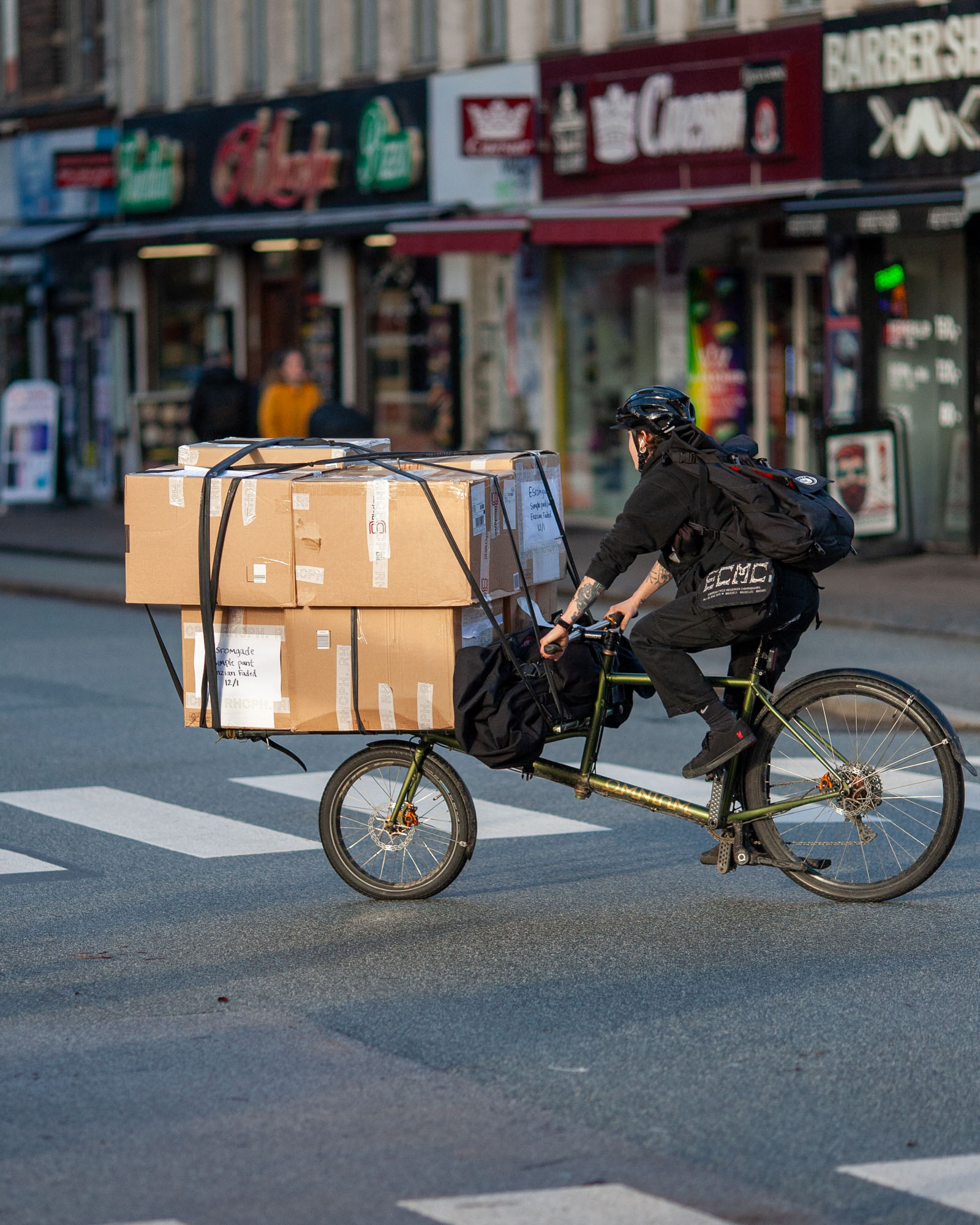 A currier riding a Omnium Cargo v3 bike in a urban enviroment