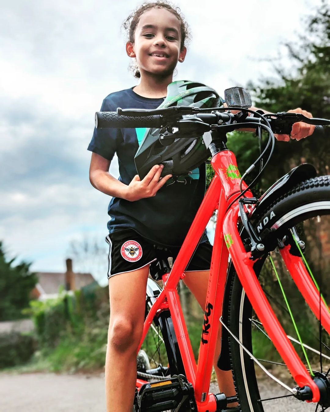 A kid sitting on a red Frog 61 bike