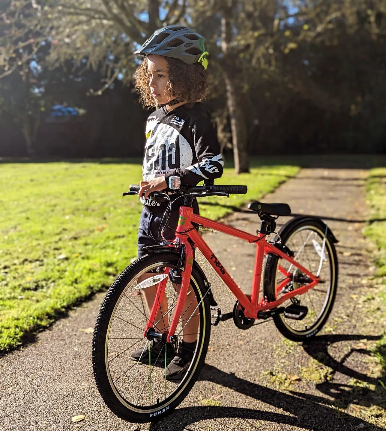A kid standing next to a red Frog 61 bike