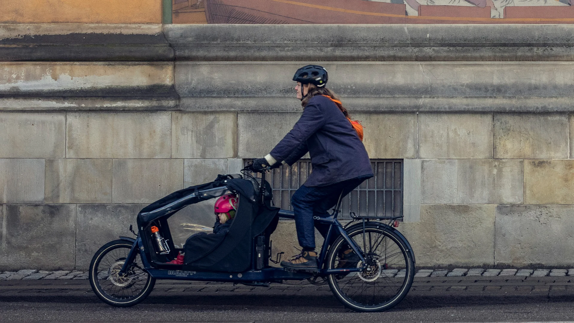 A woman riding a Bullitt cargo bike with child sitting in the canopy