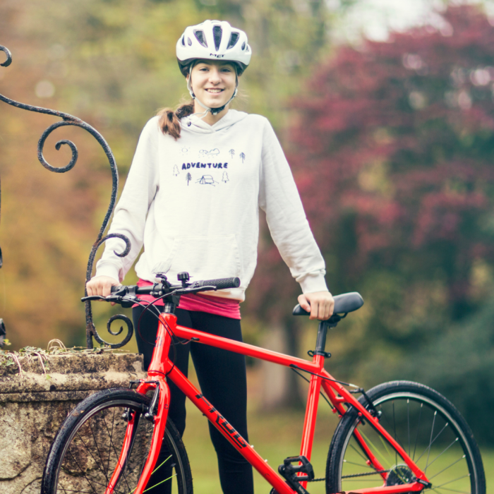 A girl standing with a red Frog 67 bike