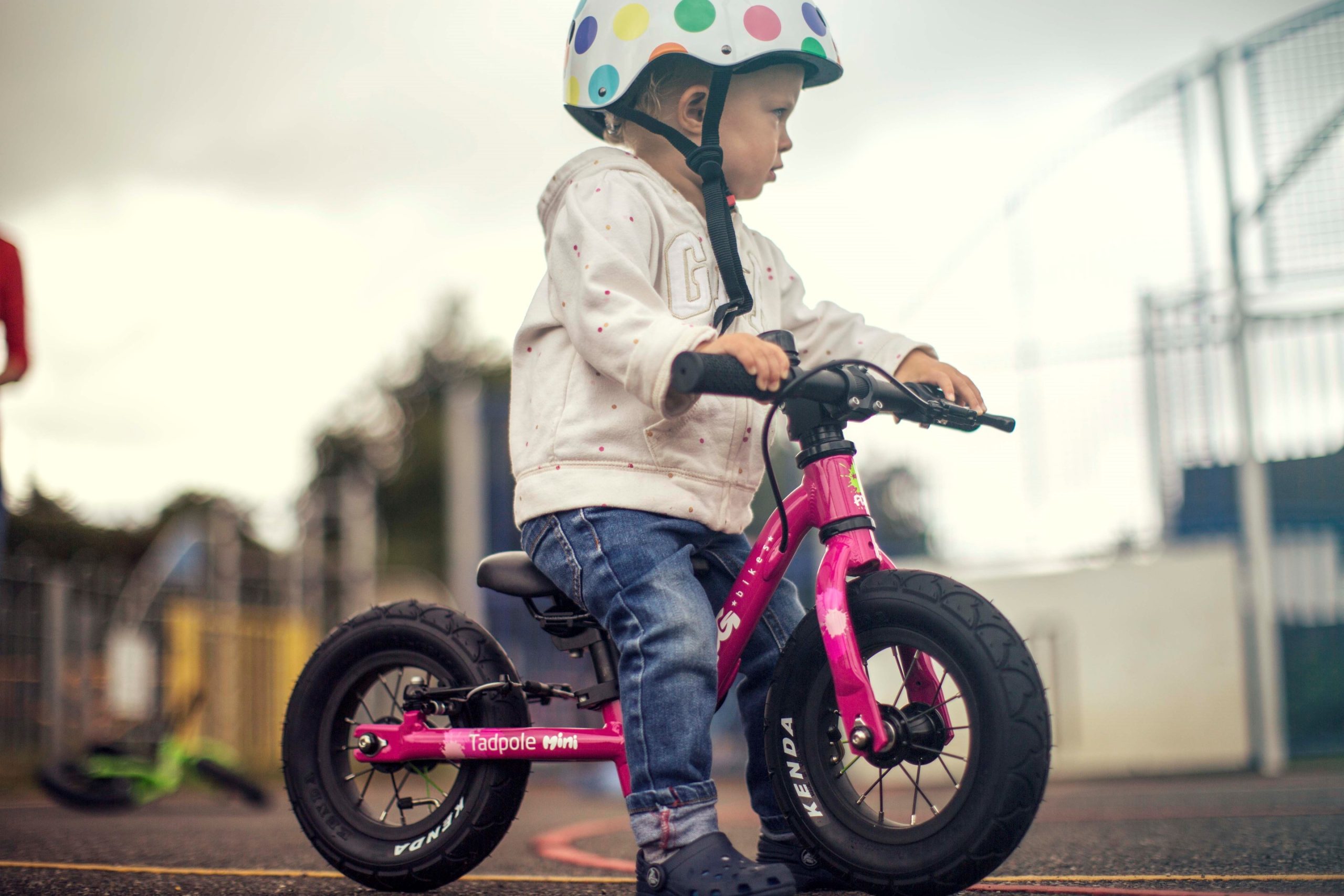 A child on a pink Frog Tadpole Mini bike on a playground