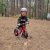 A child on a red Frog Tadpole Mini bike in a forest
