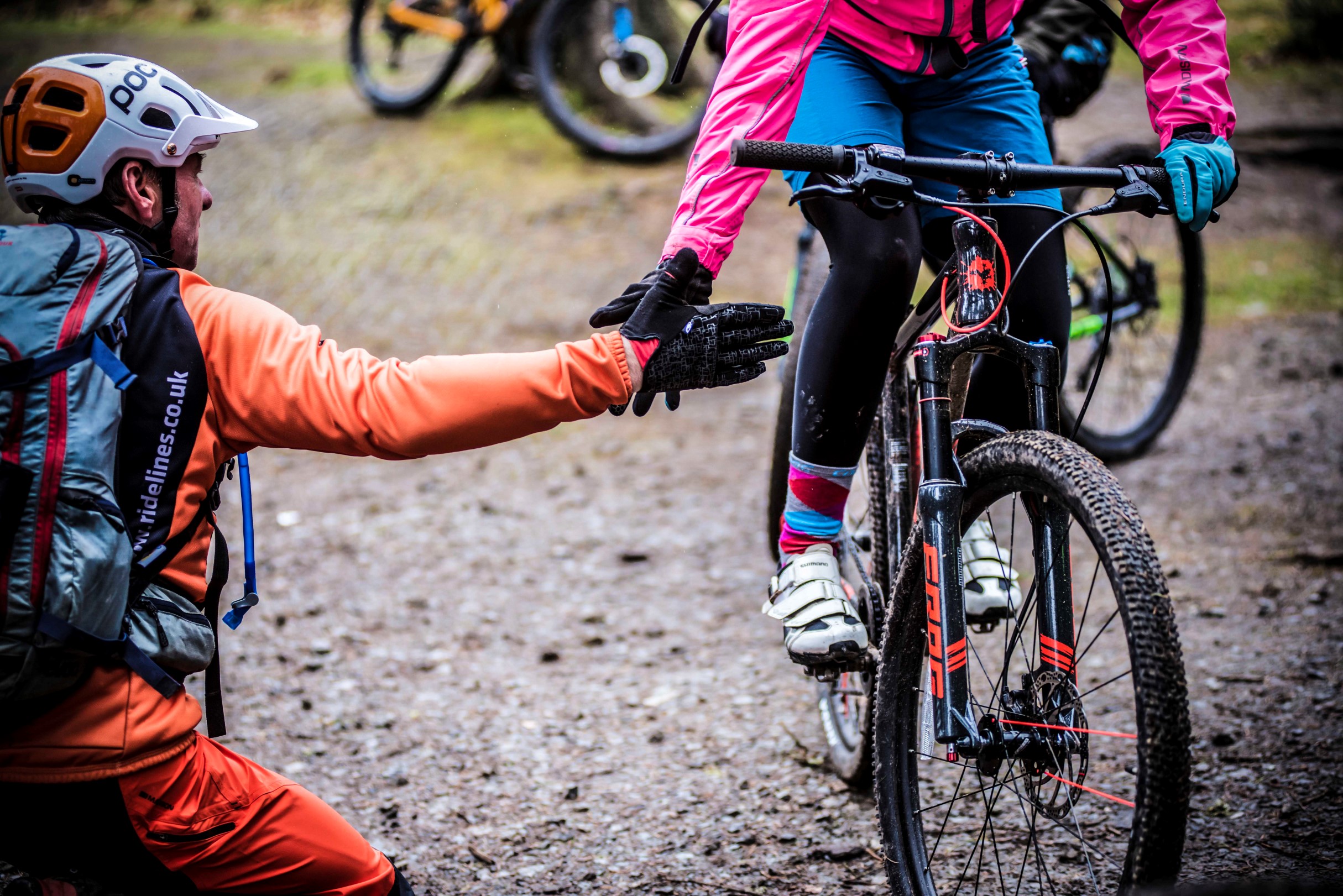 A kid riding a Frog Mountain bike giving a five to his coach